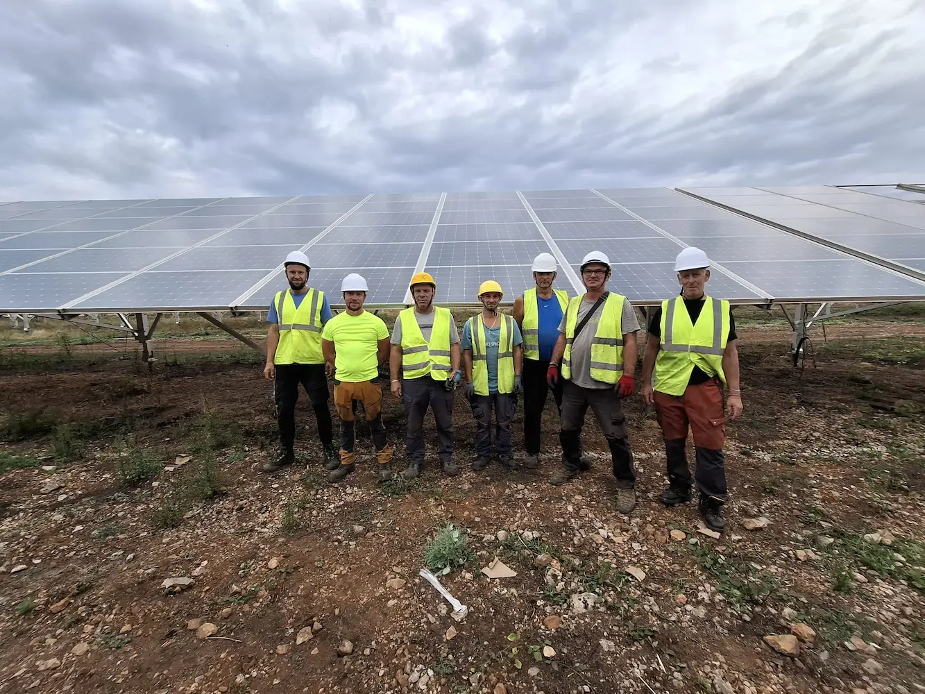 Sept membres des équipes de pose MCK Services devant une rangée de modules photovoltaïques